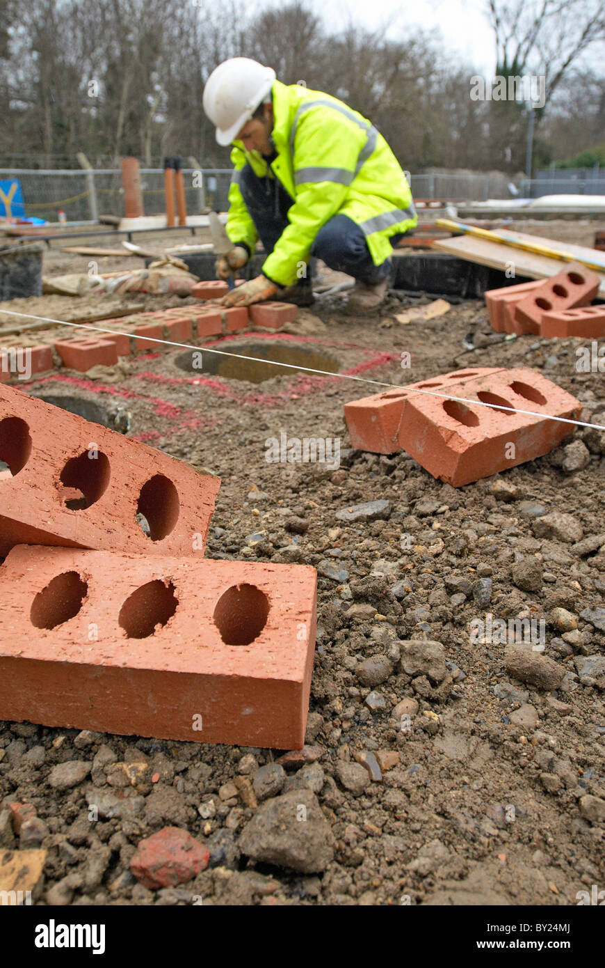 Construction worker laying bricks around utility pipes Stock Photo Alamy