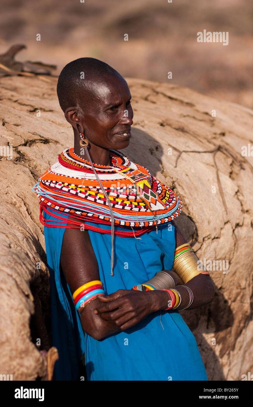 Kenya, Samburu District.  A Samburu woman, wearing intricate beaded necklaces, leans against her mud hut towards the end of the Stock Photo