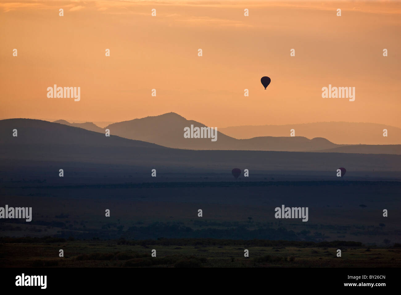 Dawn breaks over Masai-Mara as hot air balloons drift over the plains. Stock Photo