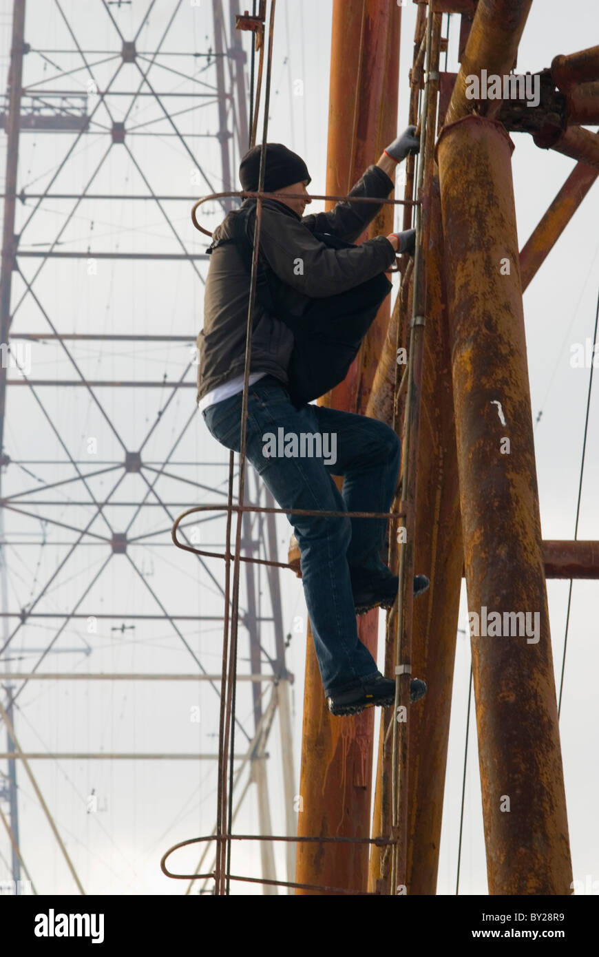 A man climbing up a metal ladder of an radio antenna, going for a BASE