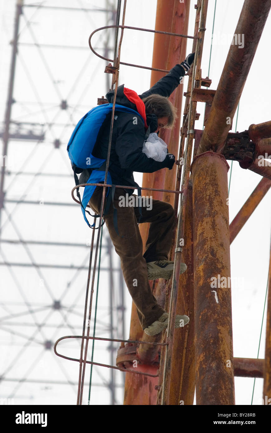 A man climbing up a metal ladder of an radio antenna, going for a BASE