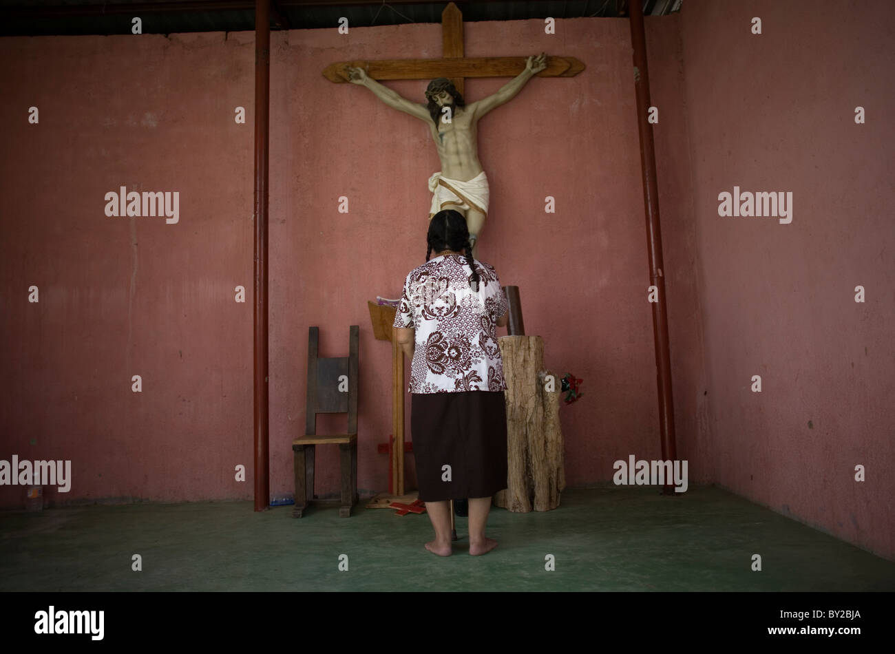 A woman prays in the chapel of a shelter for migrants located along the railroad in Ixtepec, Oaxaca, Mexico. Stock Photo