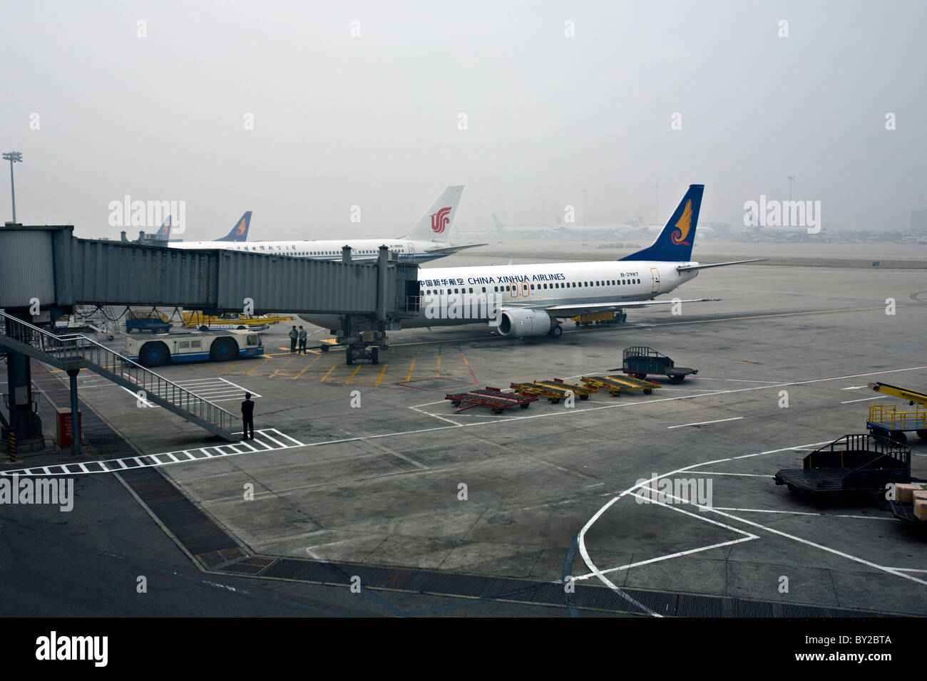 CHINA, BEIJING: China Xinhua Airlines domestic jet at the gate at Beijing Capital International Airport through air pollution Stock Photo