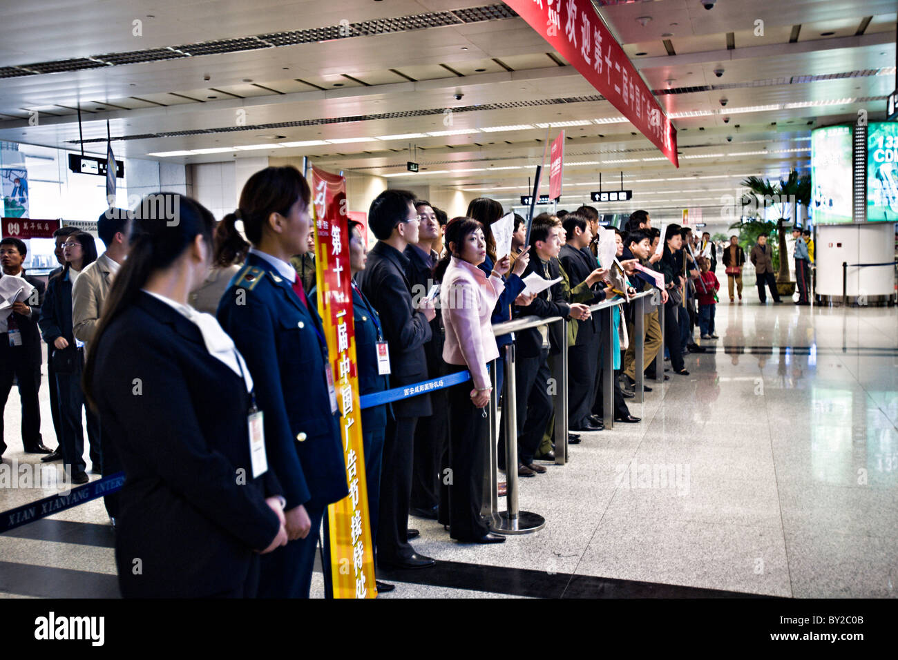 CHINA, XIAN: Xian Xianyang International Airport with Chinese people waiting behind a security line with signs Stock Photo