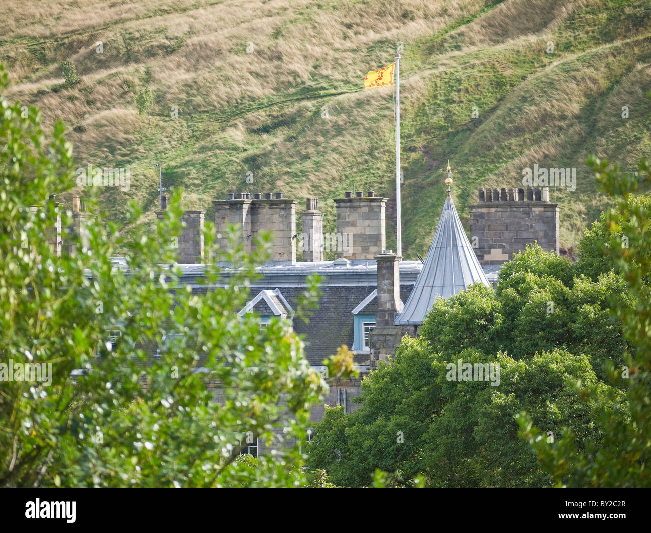 The Queens residence, Holyrood Palace, through the trees with Arthur's Seat in the background, Edinburgh, Scotland. Stock Photo