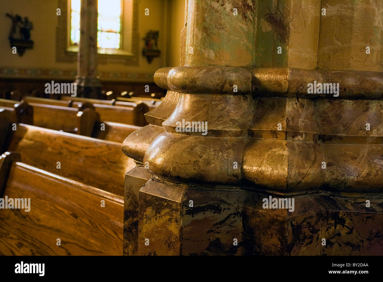 Hand painted faux marble pillar base is illuminated by afternoon sunshine in St Stanislaus Kostka Church in Adams, MA. Stock Photo