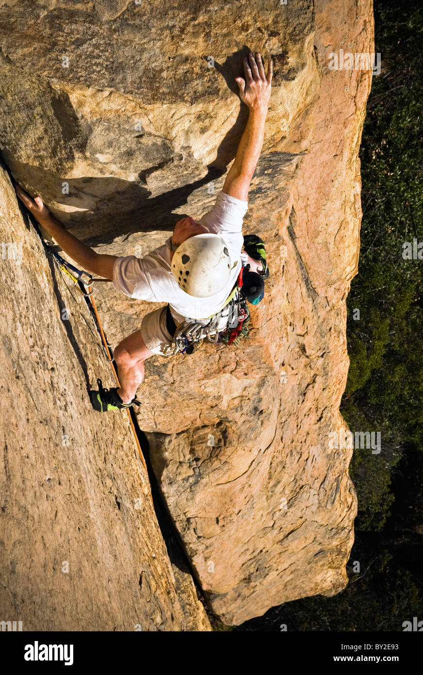 A rock climber reaches for the top on a sandstone crag in Santa Barbara