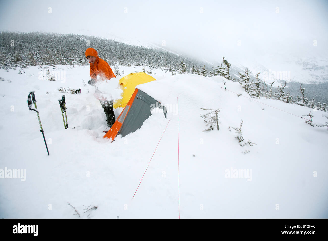 A man shovels snow away from his tent after spending the night, camped out on Mt. Washington. Stock Photo