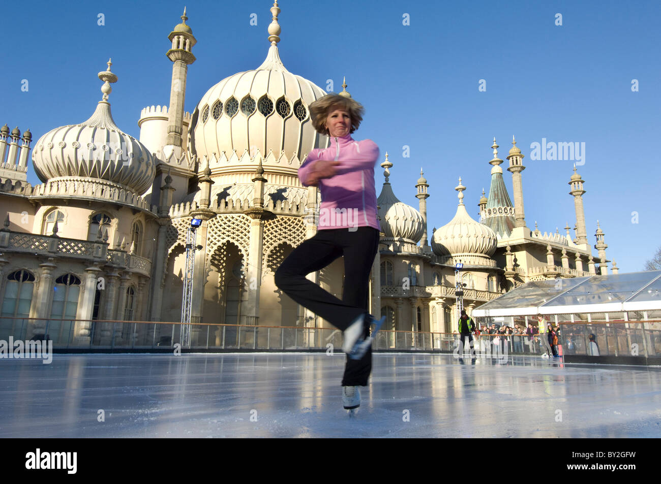A woman skater spins on the temporary pop-up ice skating rink in front of the Brighton Royal Pavilion. Stock Photo