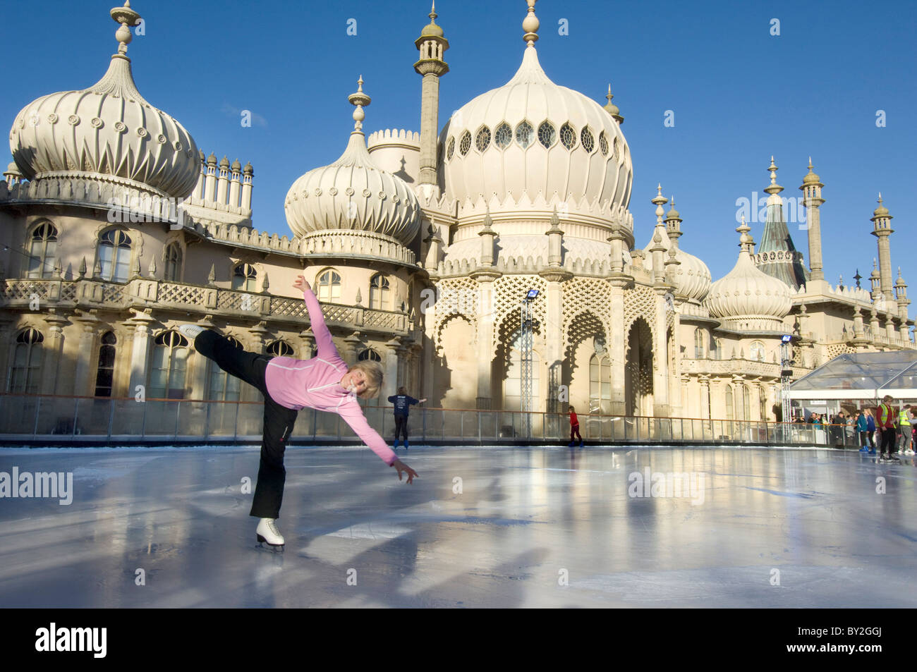 A woman skater on the temporary pop-up ice skating rink in front of the Brighton Royal Pavilion. Stock Photo