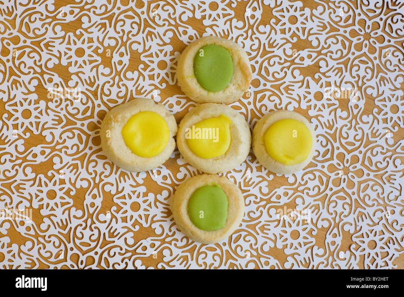 Five thumbprint cookies with icing on paper lace doily Stock Photo