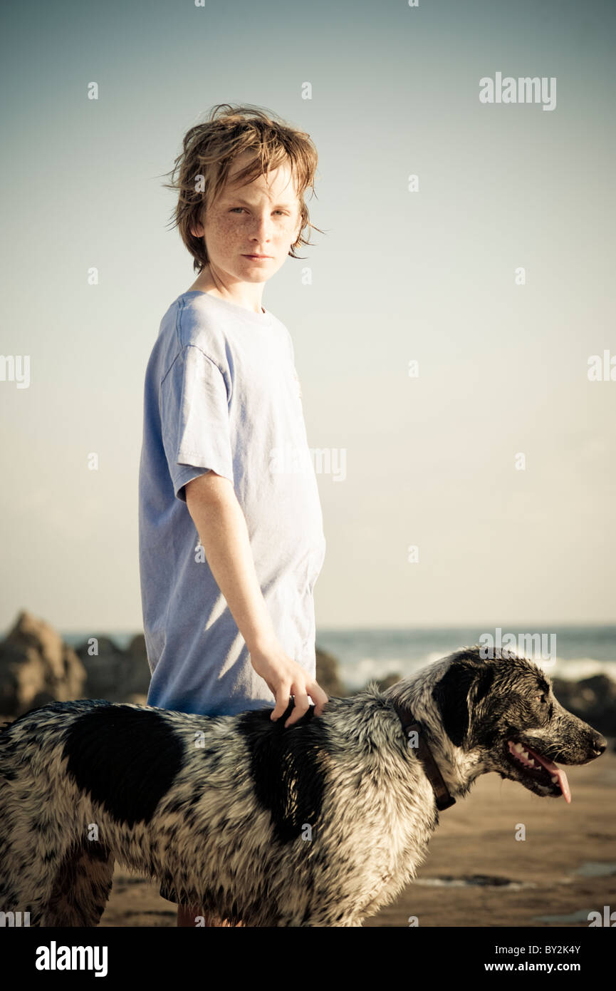 Portrait of a young boy and his dog at sunset on a quiet beach in Mexico. Stock Photo