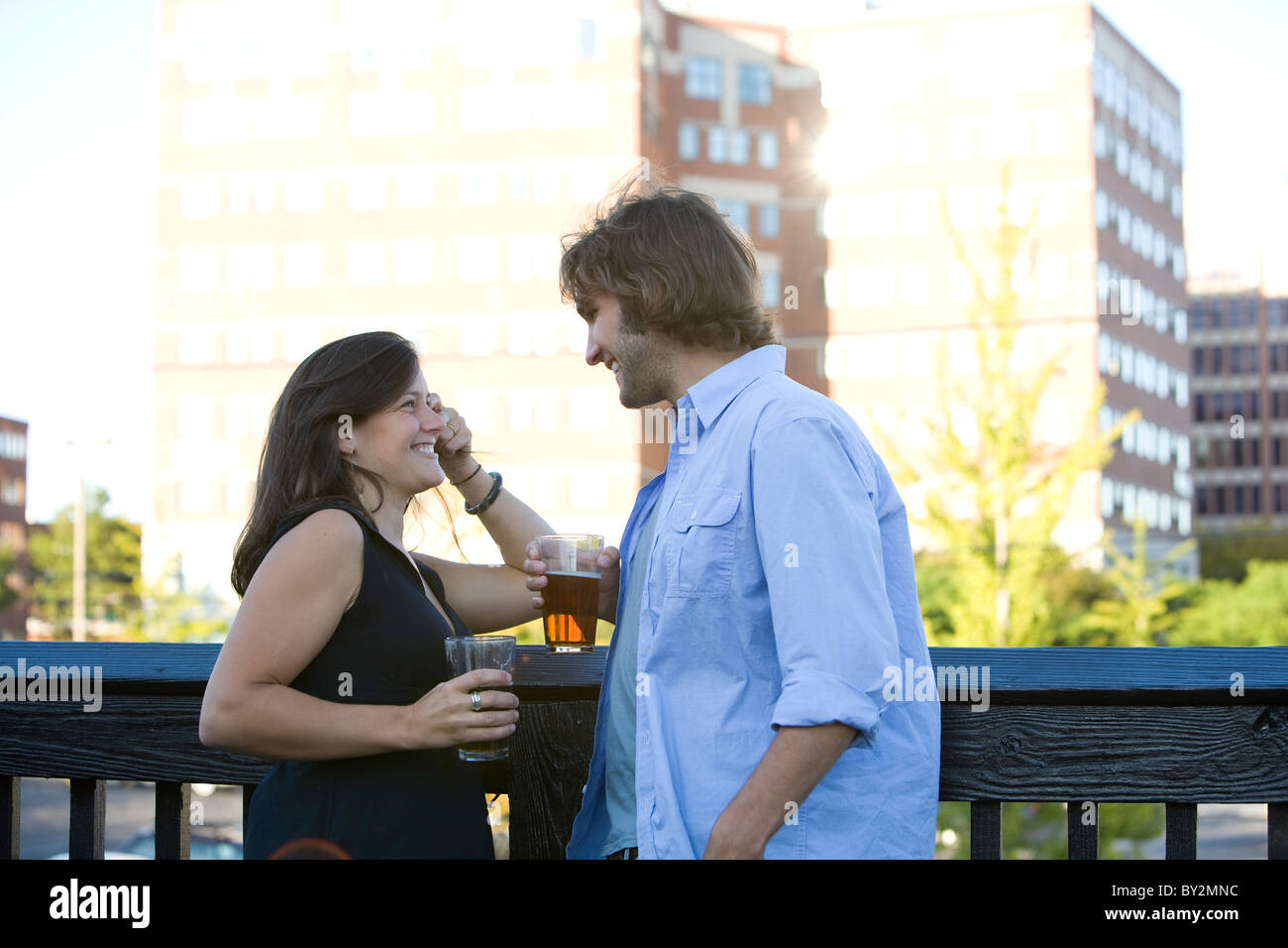 A couple smiles and chats as they enjoy a beer on the deck of a local Irish Pub in Portland, ME. Stock Photo