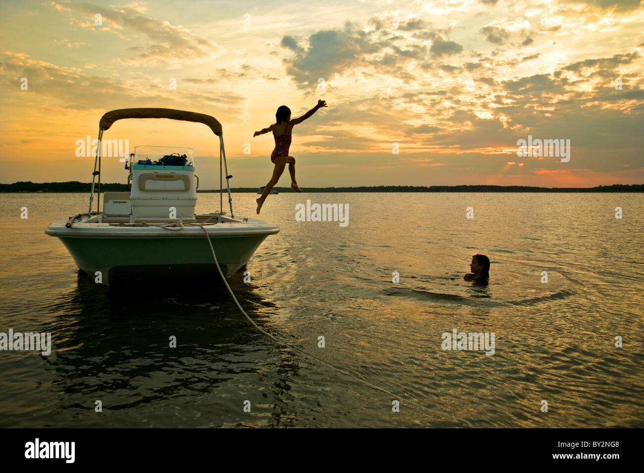 Children jumping off boat into water at sunset. McIntosh County, GA