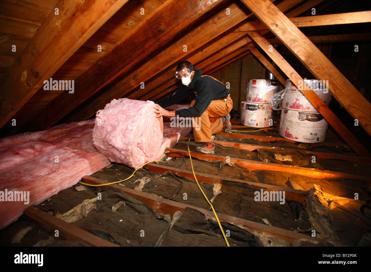 Man adds insulation to an attic Stock Photo