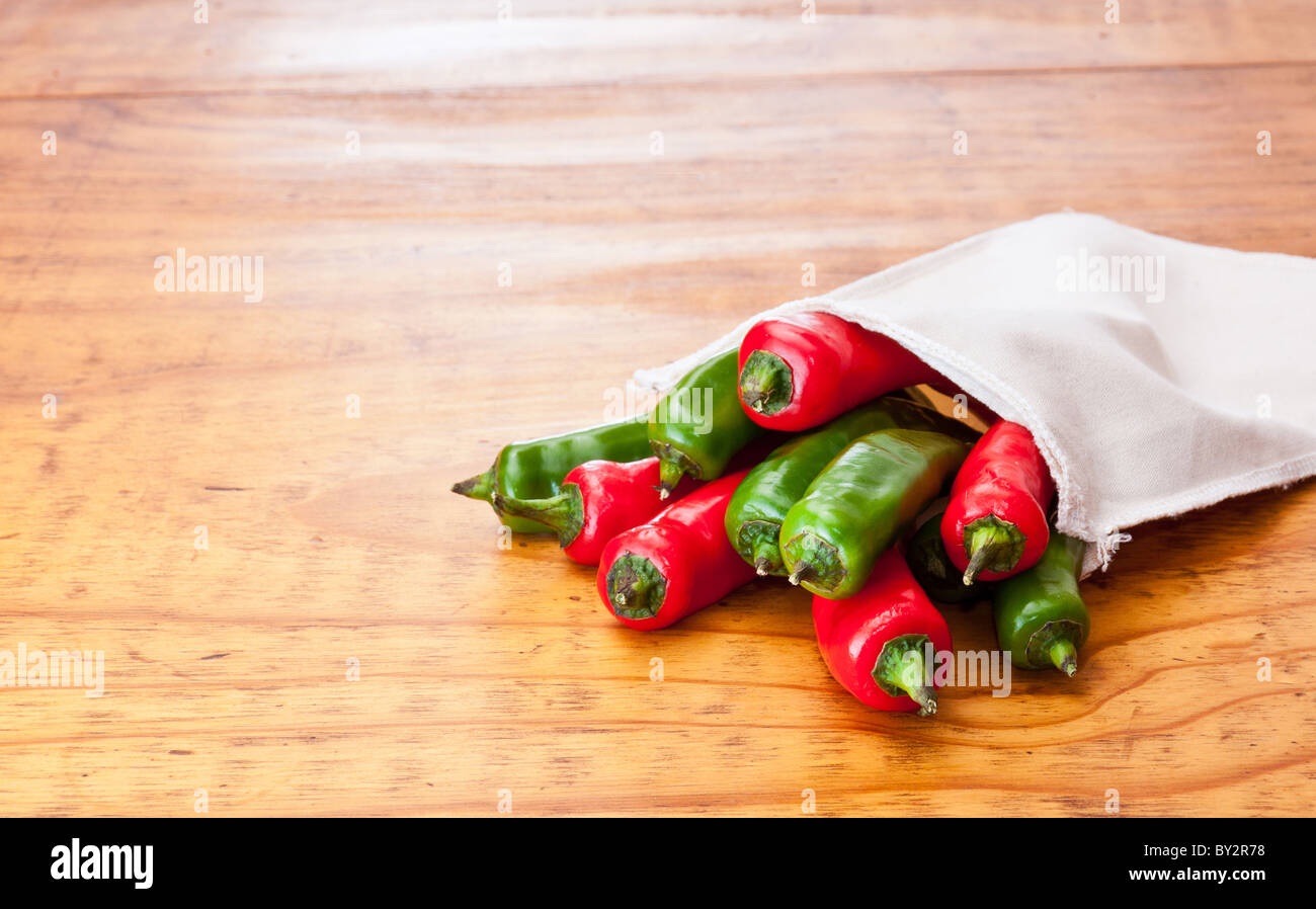 Fresh green and red chili peppers in a cloth bag, displayed on a ...