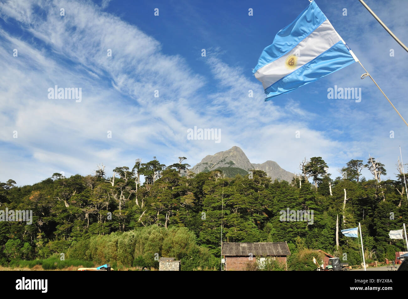 Blue sky, green mountain view of Argentinian Flag flying from the mast of a catamaran moored at Puerto Blest, Andes, Argentina Stock Photo