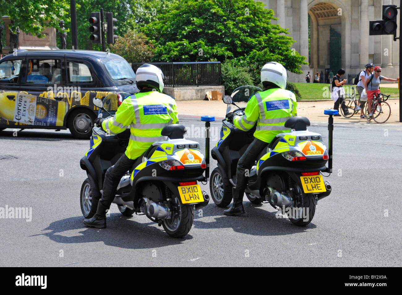 Two Metropolitan Police Community Support Officers wearing crash helmets riding Piaggio MP3 three wheeled scooters Hyde Park Corner London England UK Stock Photo