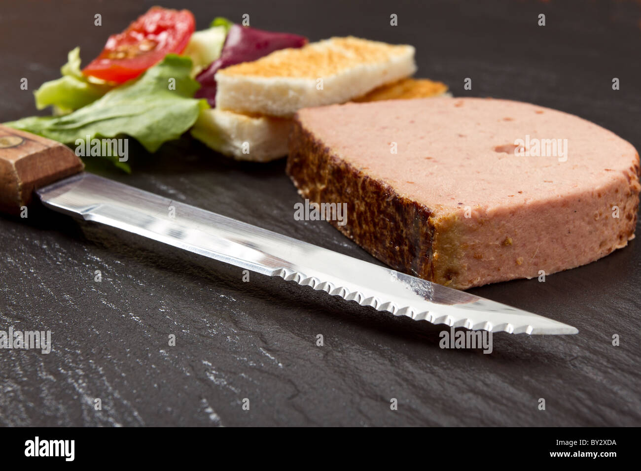 Pate Apetiser with melba toast soldiers and small salad on dark slate background. Stock Photo