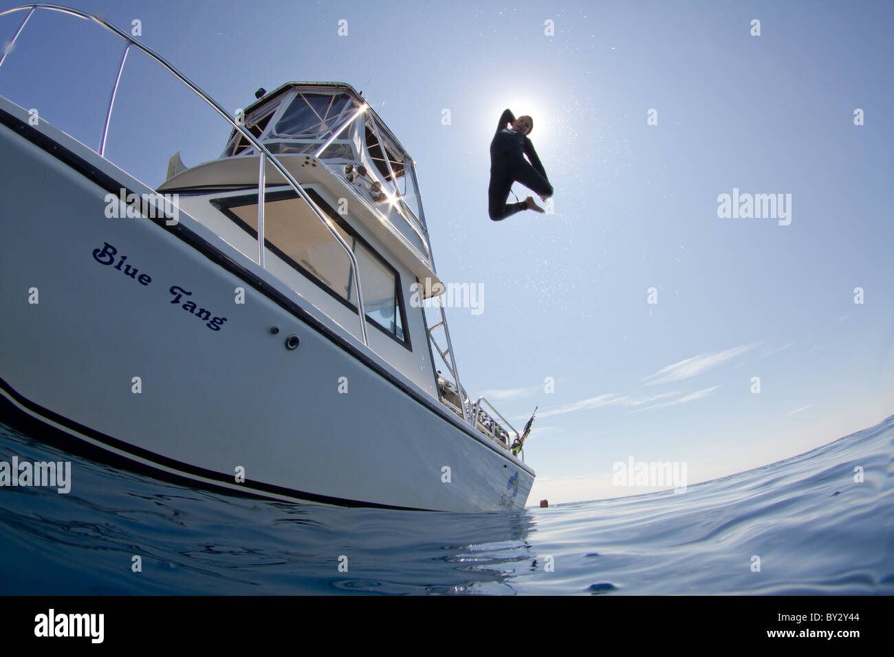Teenage Boy Jumping off of Dive Boat Stock Photo