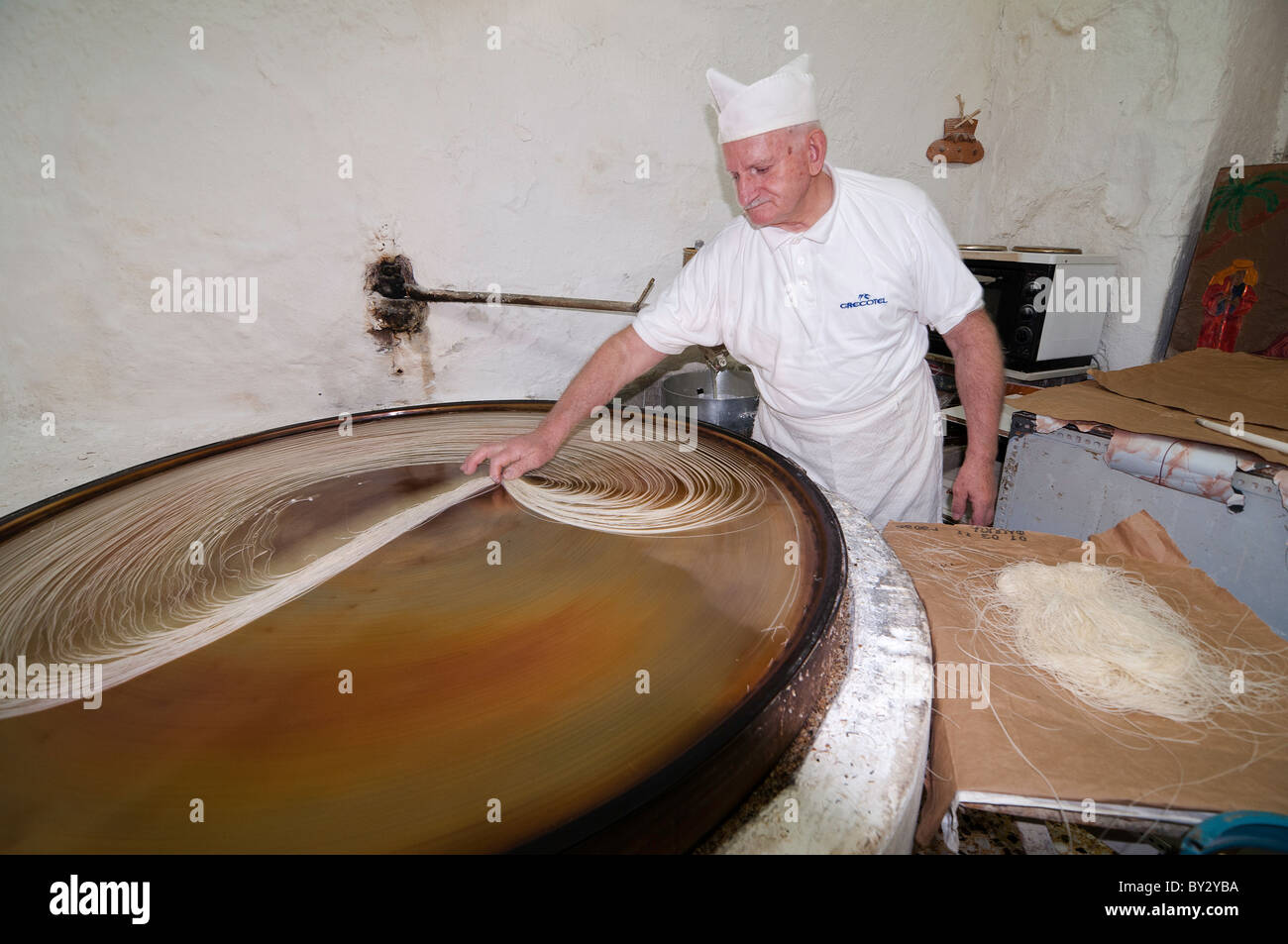 Making Kataifi. stringy filo pastry,  in the traditional way on a spinning hot plate. Rethymno, Crete, Greece Stock Photo