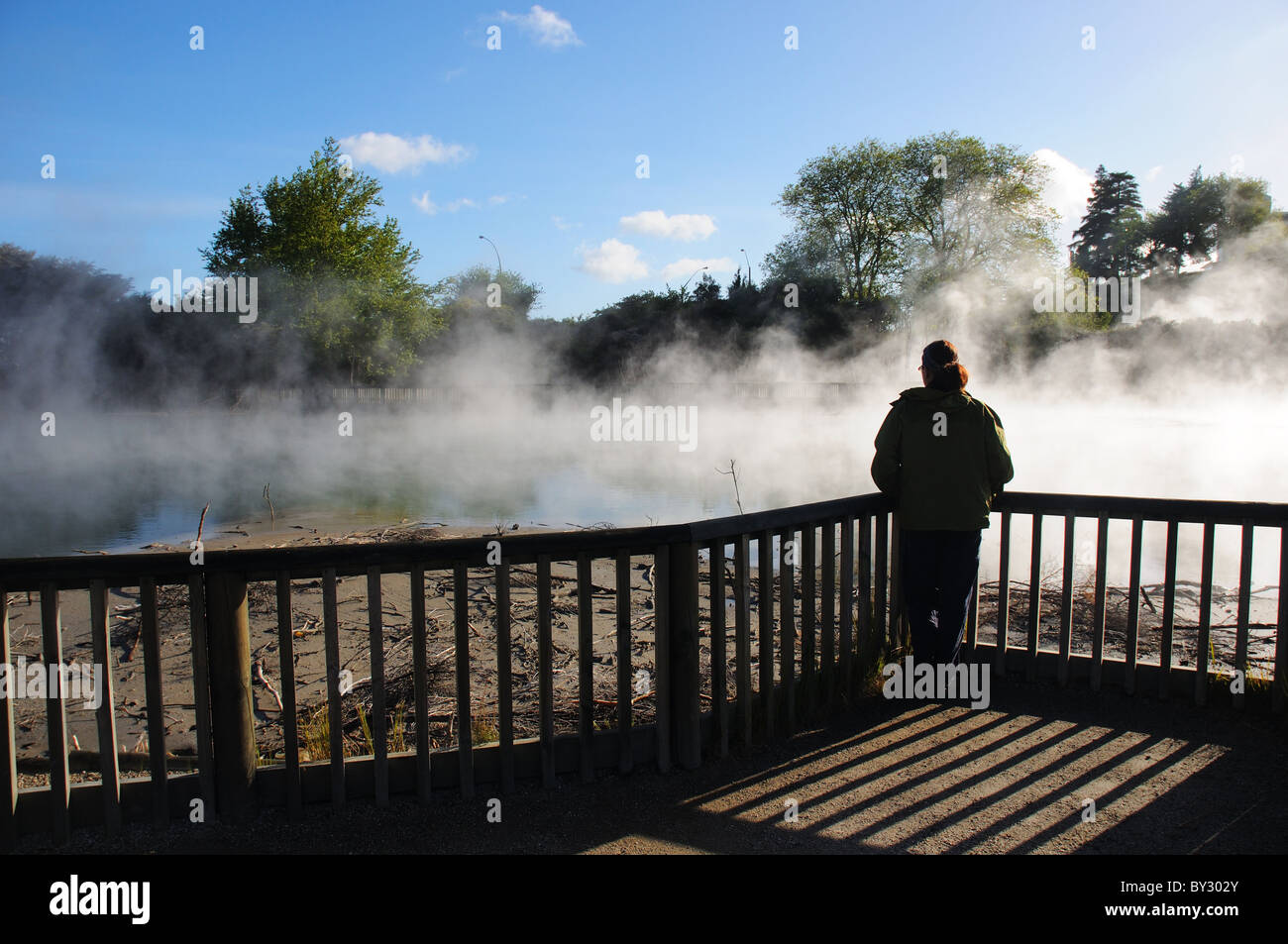 A young woman admiring the  steaming ponds in Taupo town centre, New Zealand Stock Photo