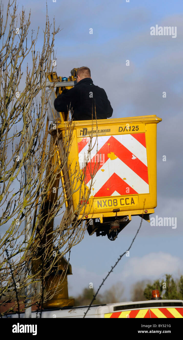 A council workman uses a cherry picker one man lifting hoist to repair a street lamp Stock Photo