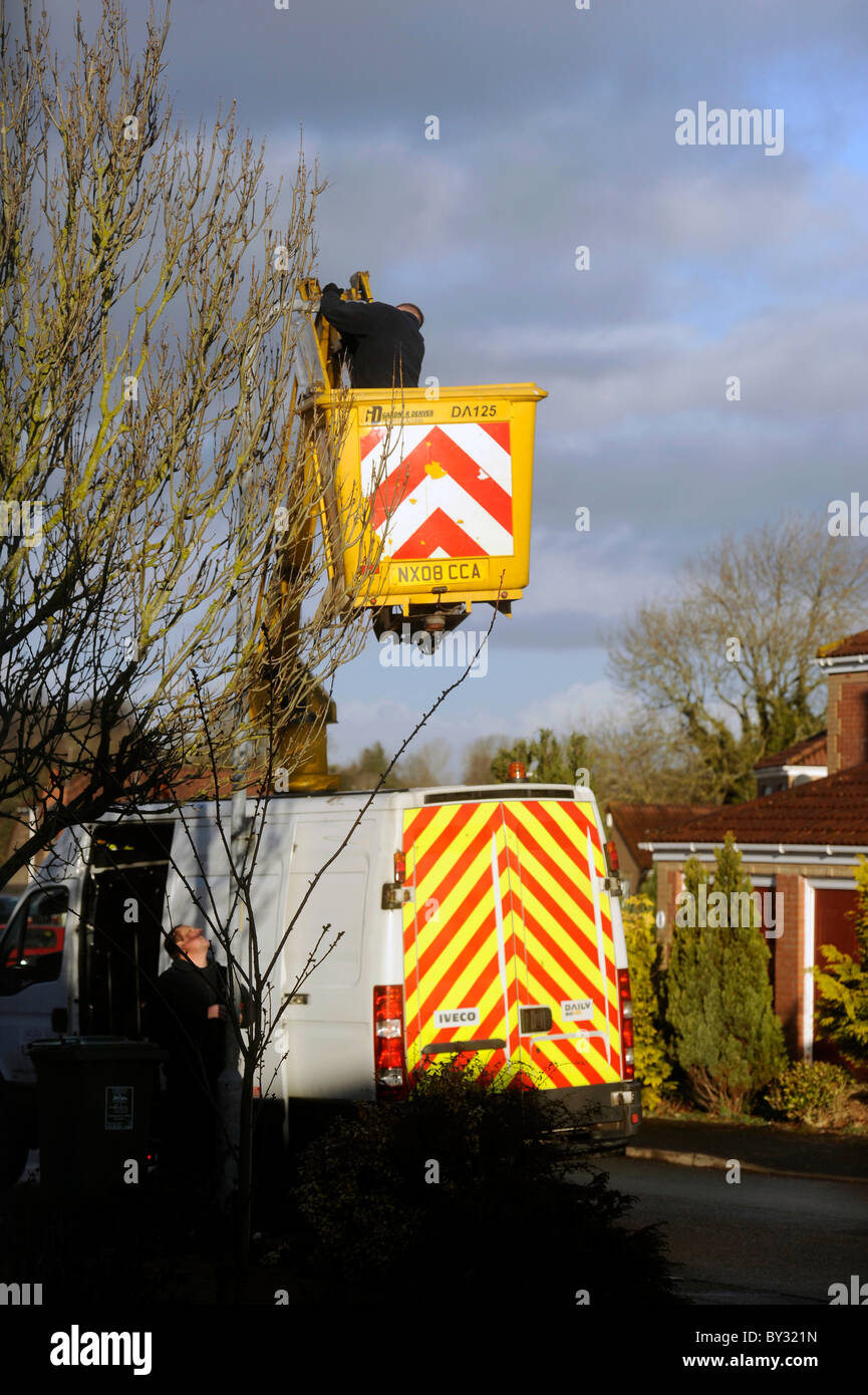 A council workman uses a cherry picker one man lifting hoist to repair a street lamp Stock Photo