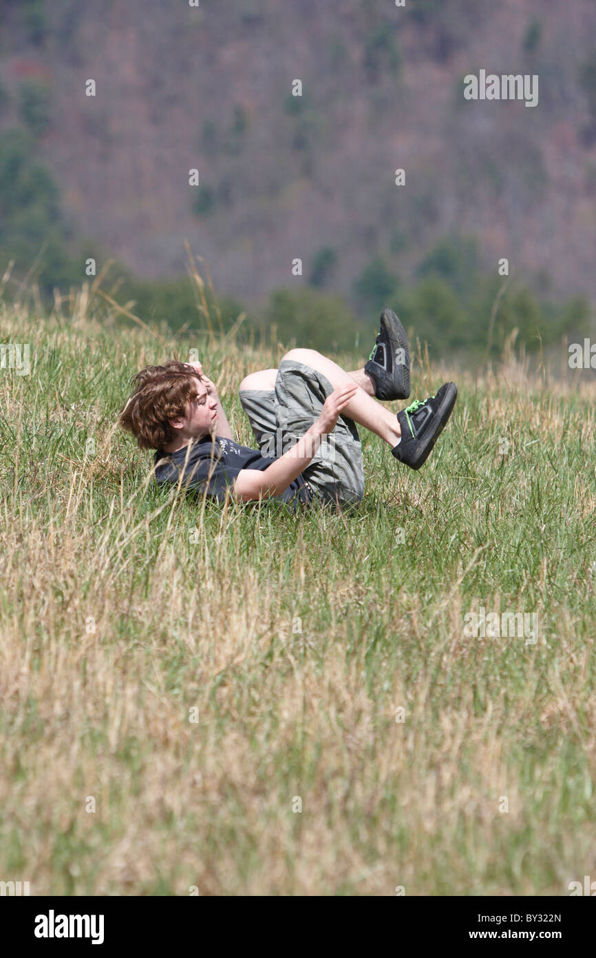 Teen boy rolling down hill Stock Photo - Alamy