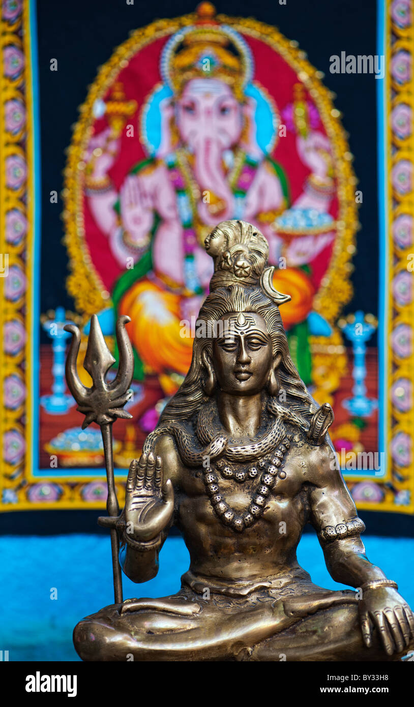 Lord Shiva, Indian Deity statue in front of Ganesha wall hanging. India Stock Photo