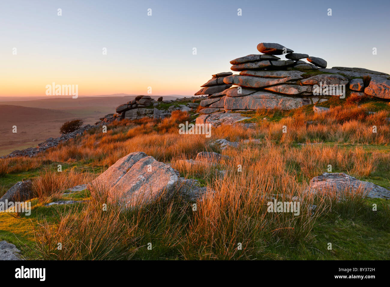 The glow of the evening sun highlights the grasses and rocky outcrop of Stowe's Hill high up on Bodmin Moor. Stock Photo