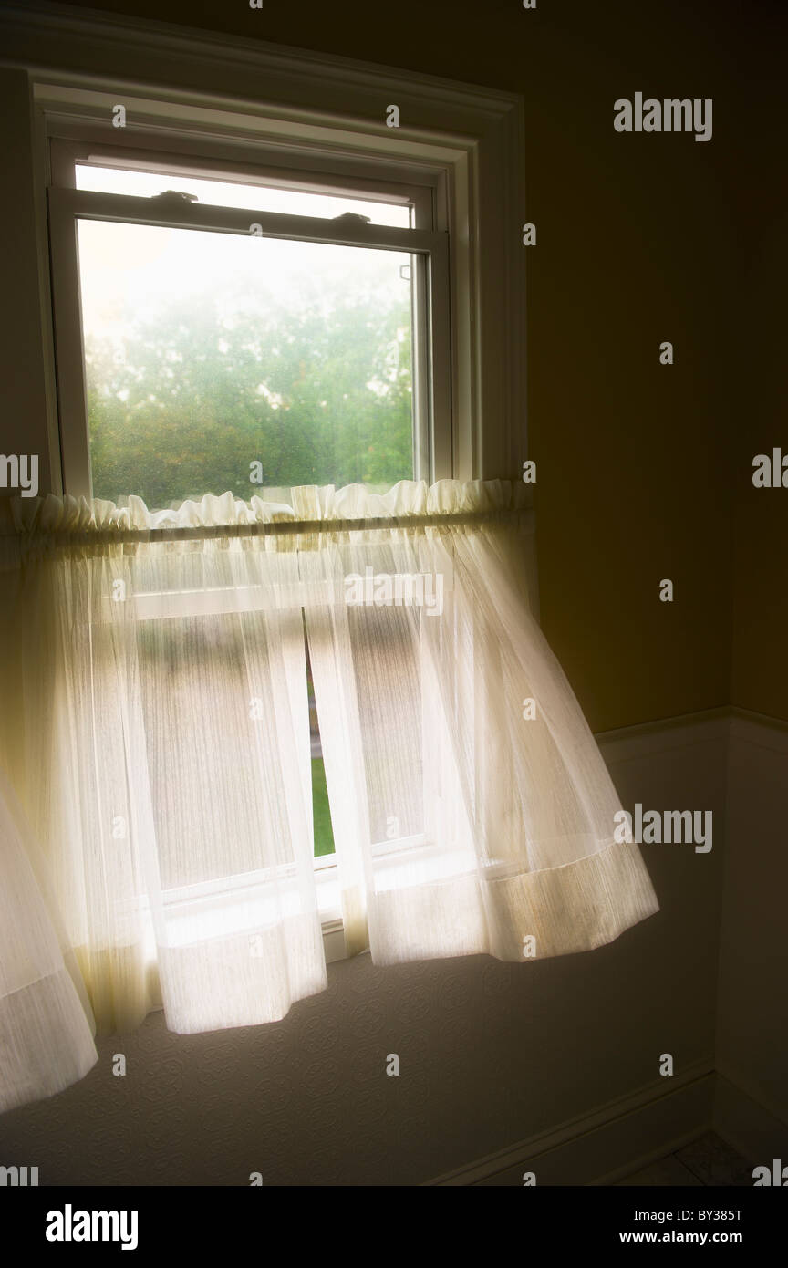 Wind blowing curtains through window Stock Photo