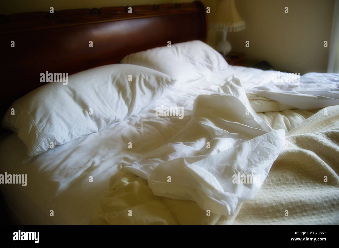 Unmade bed with white duvet Stock Photo