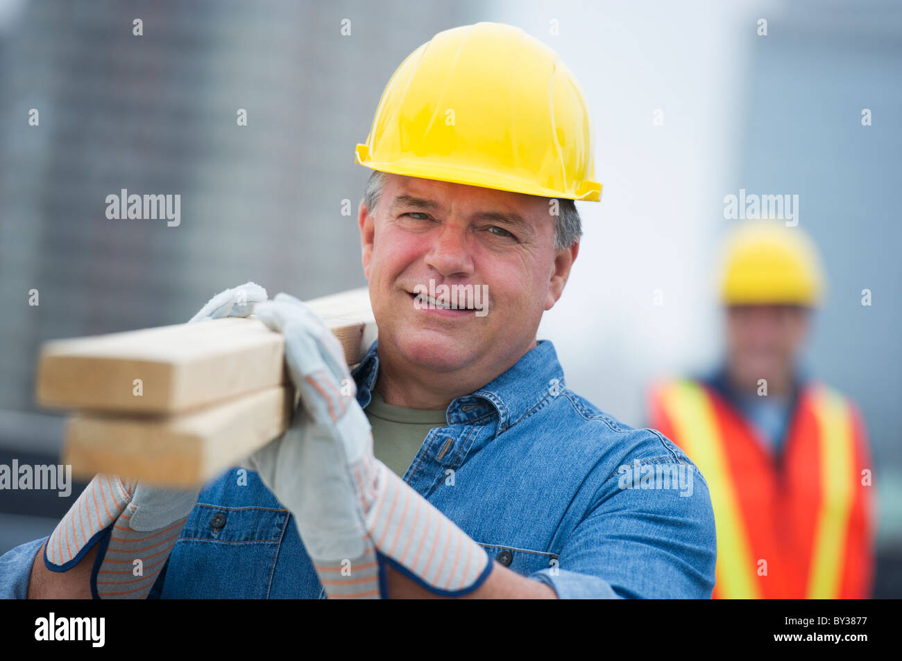 USA, New Jersey, Jersey City, Portrait of construction worker carrying planks Stock Photo
