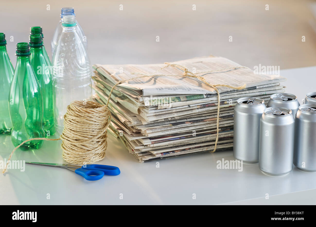 Recycling bottles, cans and newspapers with scissors and string Stock