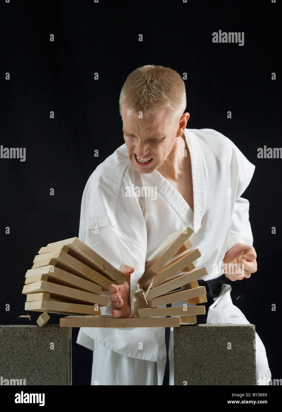 Young man breaking boards with karate chop on black background Stock Photo  - Alamy