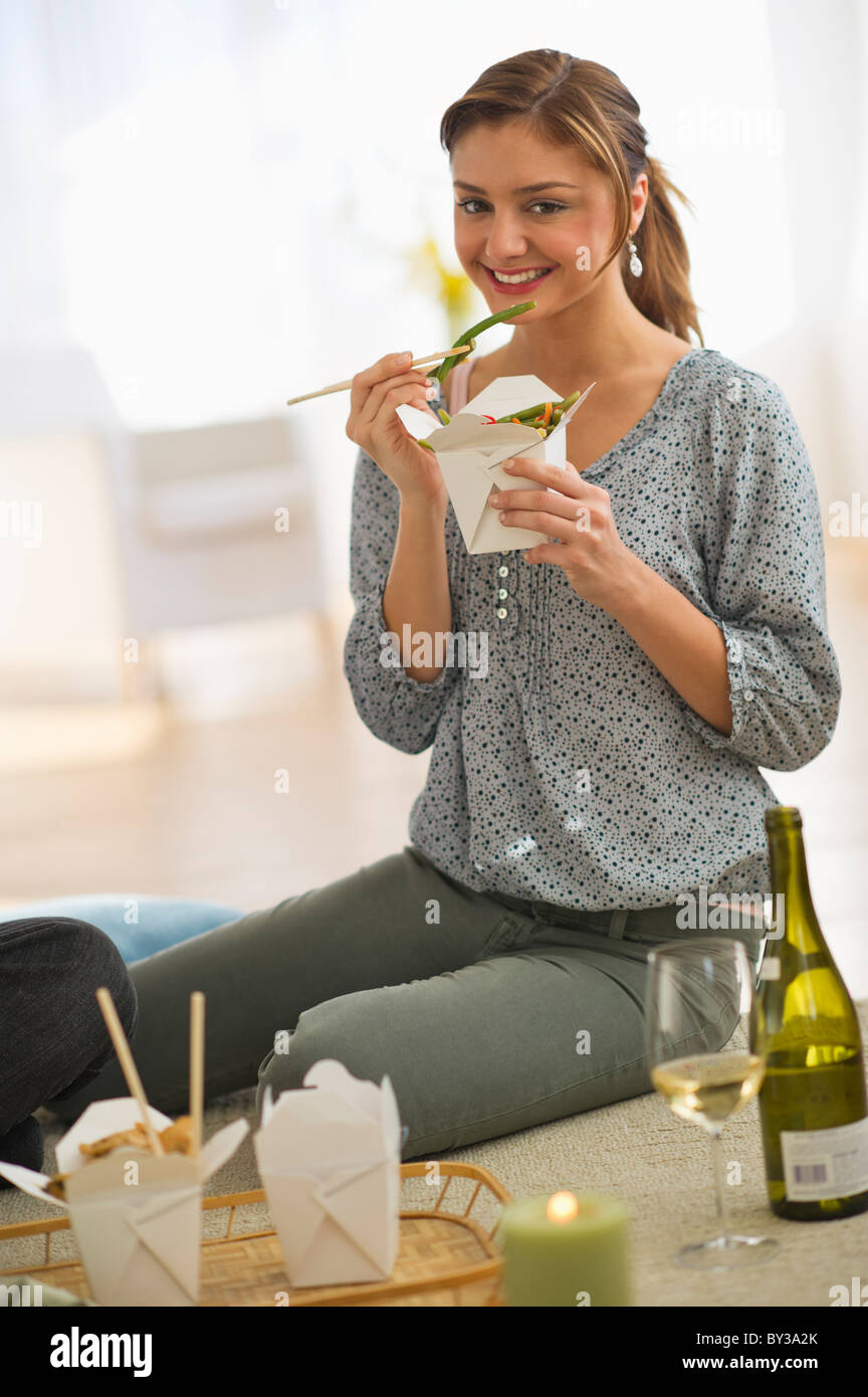 USA, New Jersey, Jersey City, Portrait of young woman eating takeaway food on floor Stock Photo