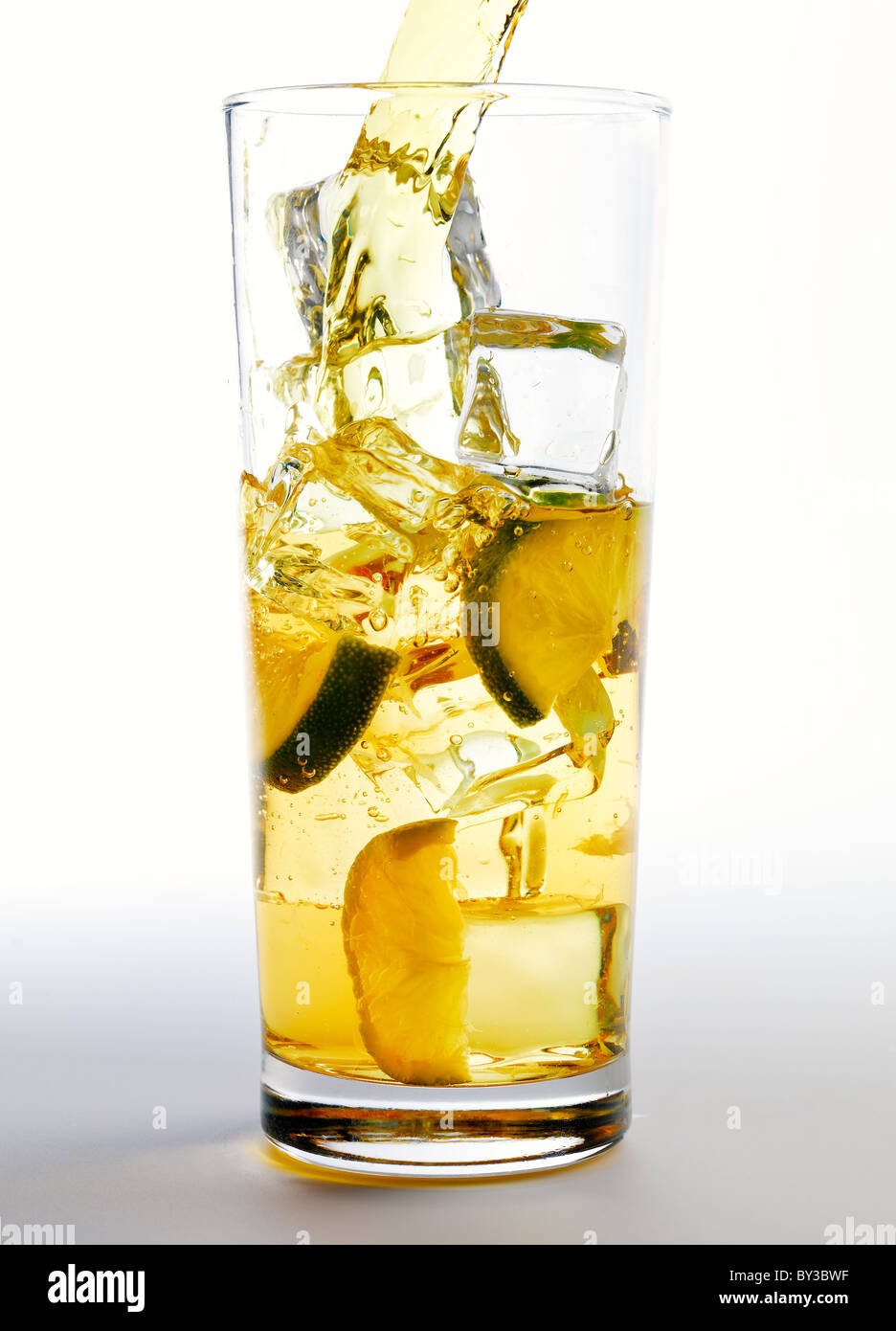 A fresh long drink (could be juice or alcoholic) being poured over ice and limes Stock Photo