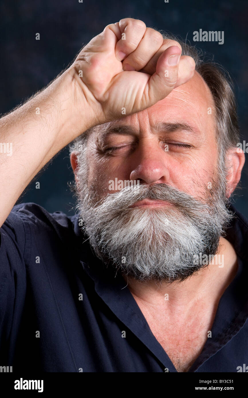 Look of disappointment on a man's face with his fist clenched on the forehead. Stock Photo