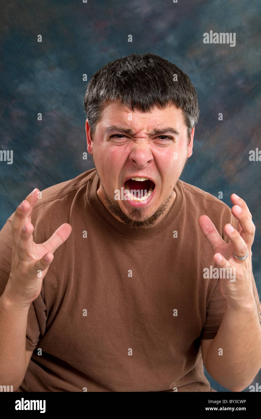 Enraged man who is close to tears, screams and gestures with his hands. Stock Photo