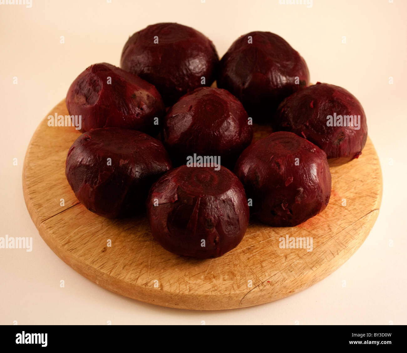 nine cooked and peeled whole beetroot on a round wooden board Stock Photo