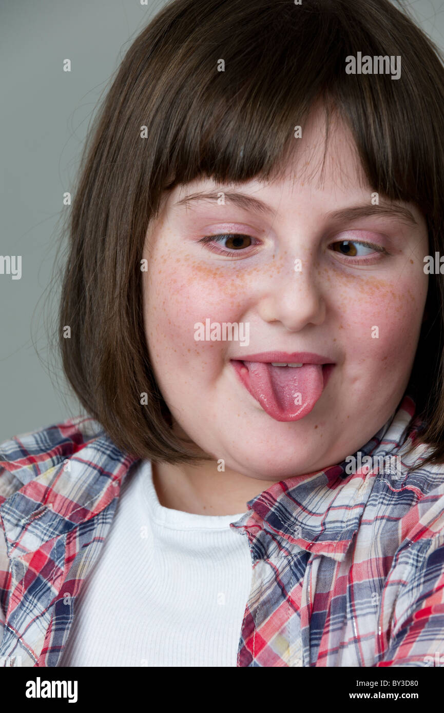 Close up portrait of young girl pulling faces, with her tongue out and