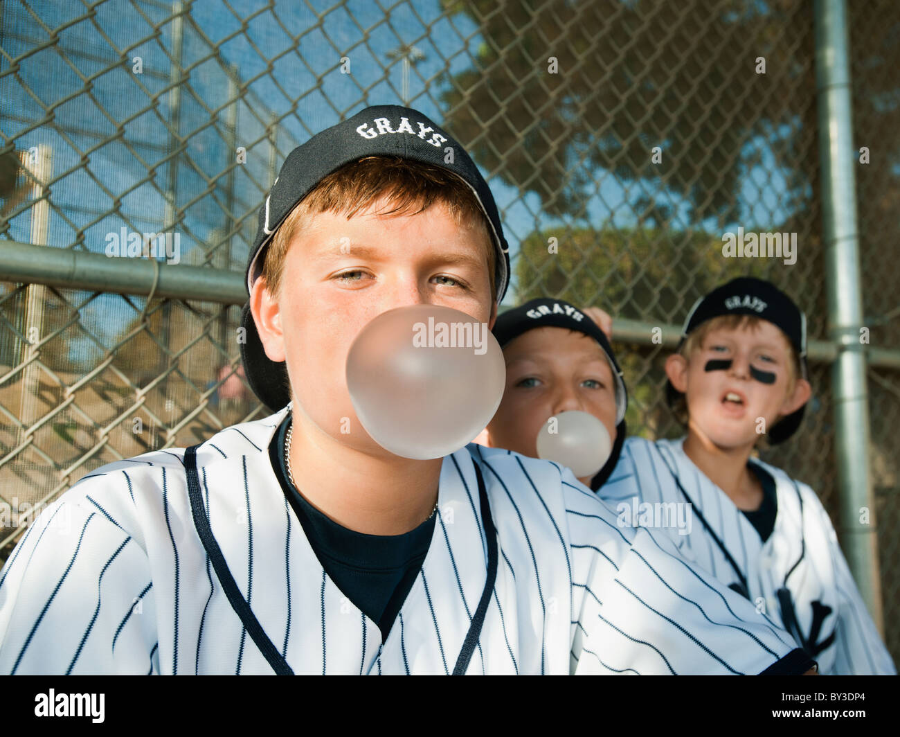 USA, California, Ladera Ranch, Boys (10-11) from little league sitting on dugout and blowing bubble gum Stock Photo