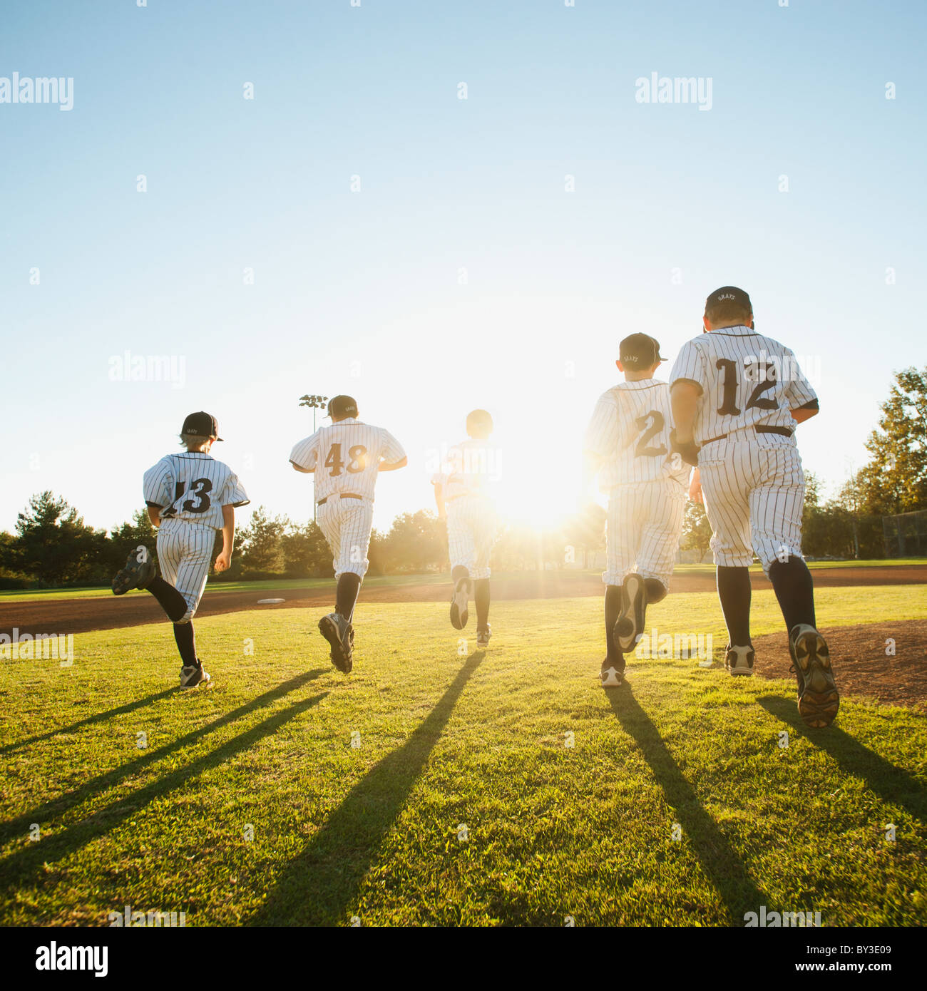 Baseball players (10-11) running on baseball diamond Stock Photo