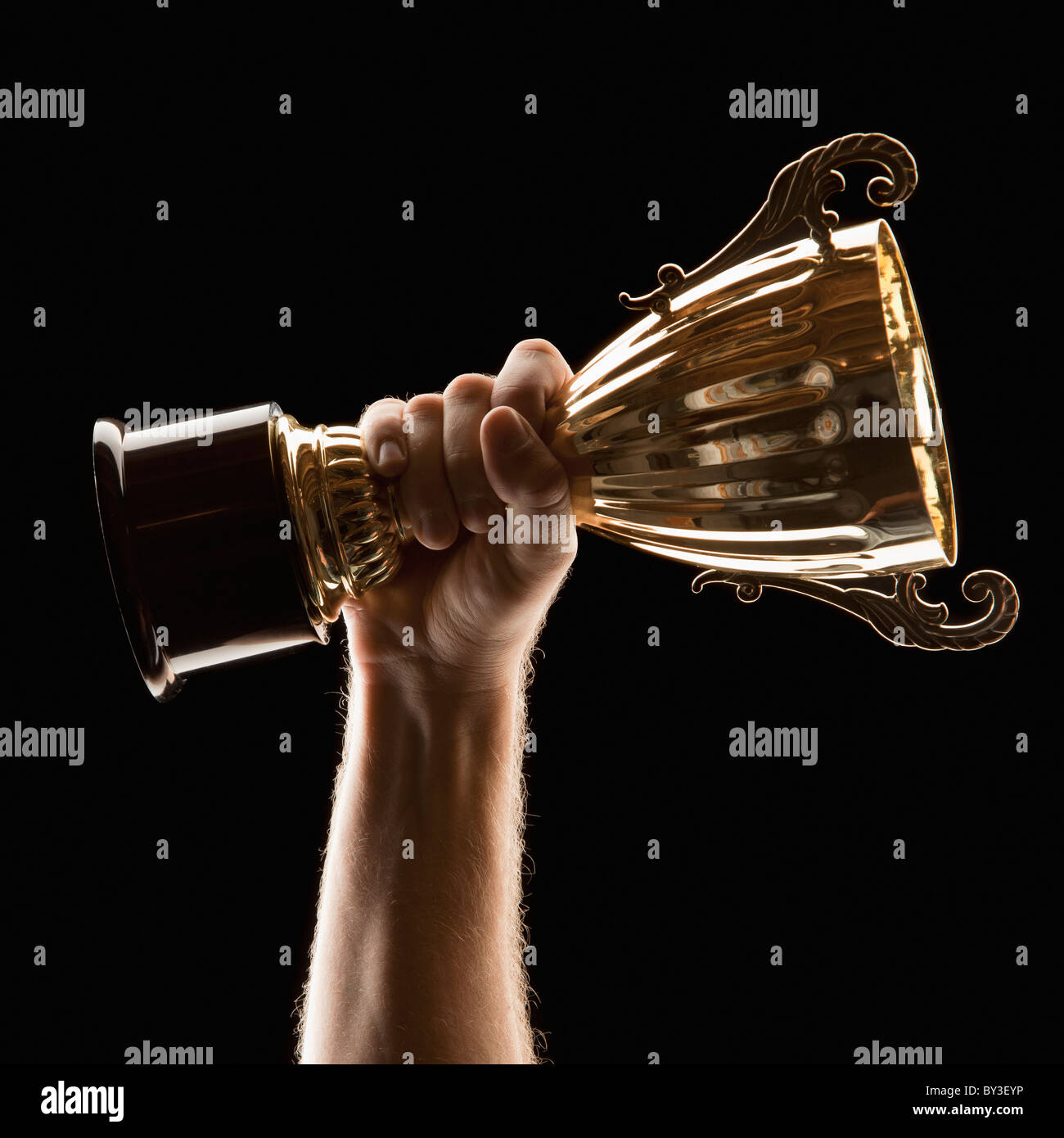 Hand holding trophy on black background Stock Photo - Alamy