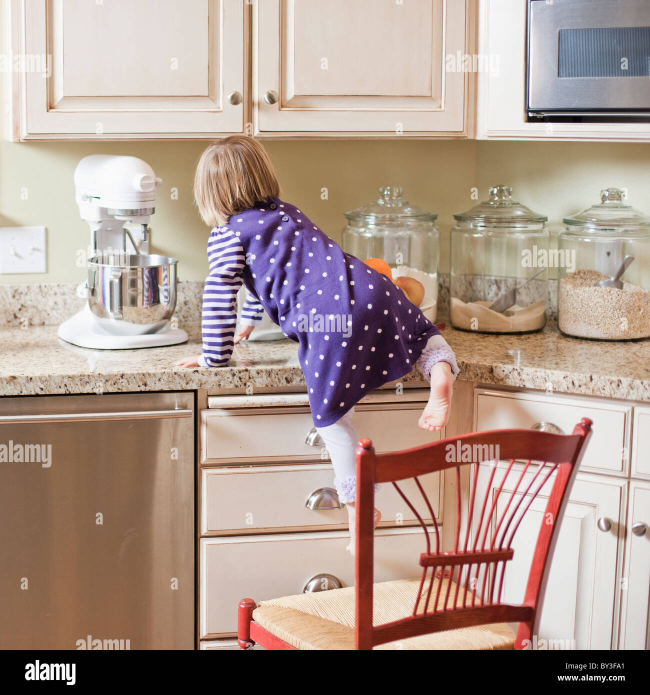 USA, Utah, Girl (23) climbing on cupboard in kitchen Stock Photo Alamy