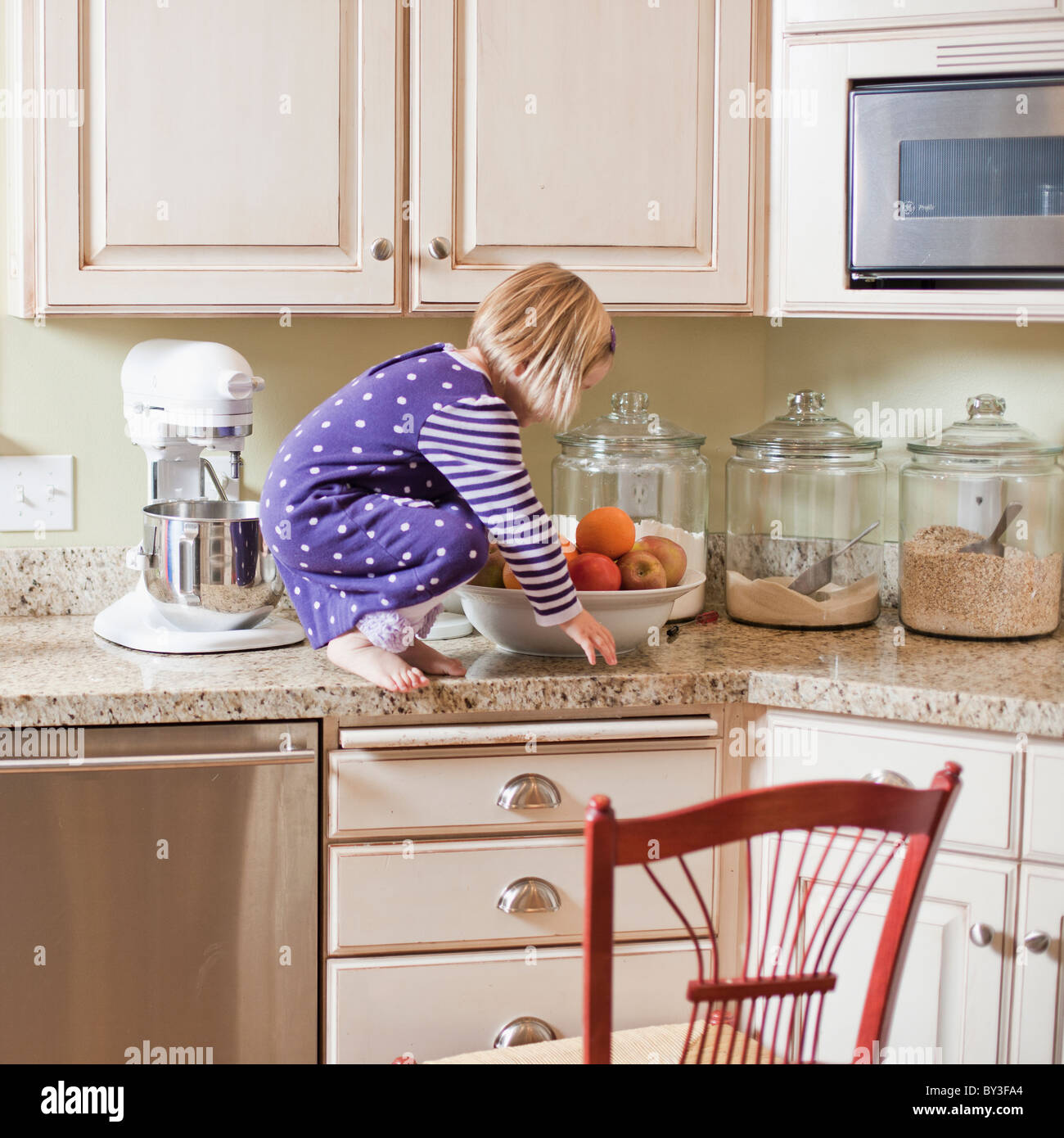 USA, Utah, Girl (23) climbing on cupboard in kitchen Stock Photo Alamy
