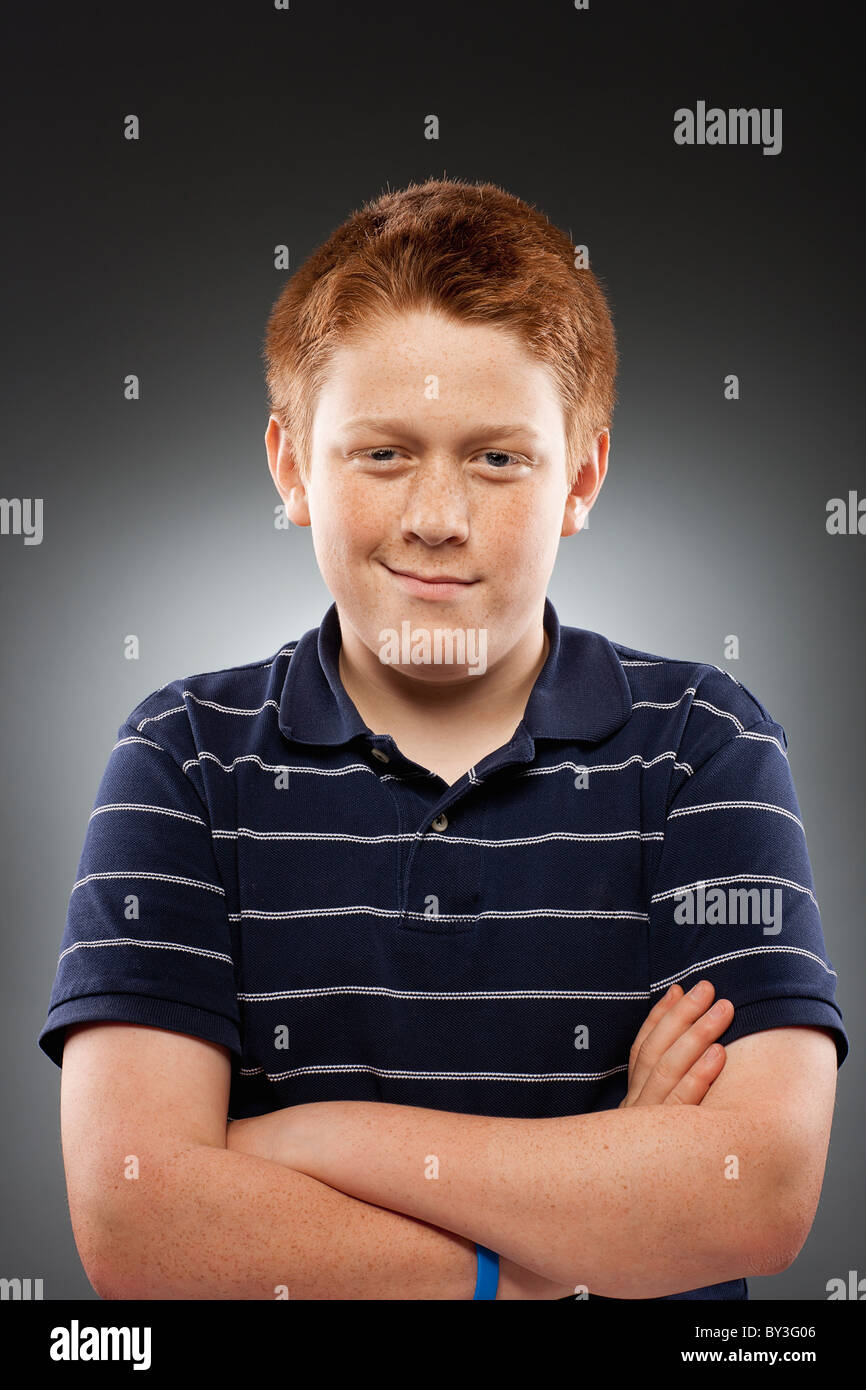 Portrait of redhead teenage boy (14-15) with arms crossed, studio shot Stock Photo