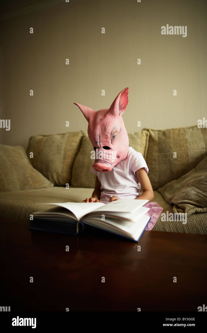 Girl in pig mask reads book Stock Photo