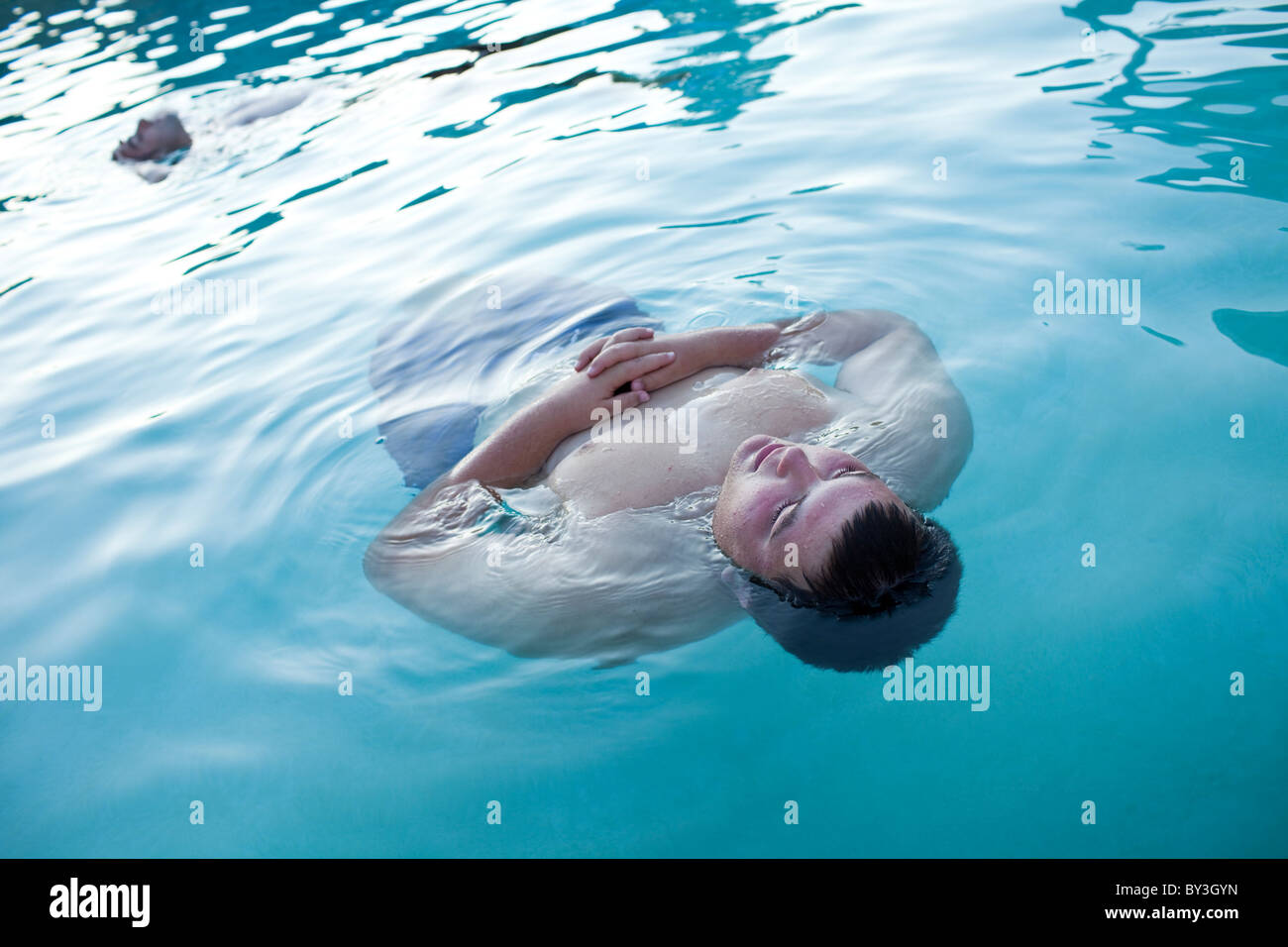 Hughson, California, United States.  An obese teenager floats in the swimming pool. Stock Photo